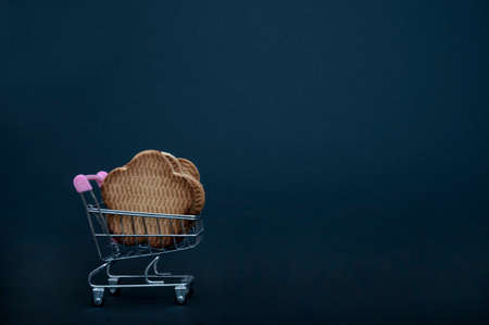 Small basket full of fresh sweet pastries in the form of cookies - isolate on black background. Close-up, side view. Large and beautiful cookies in a shopping trolley.の写真素材