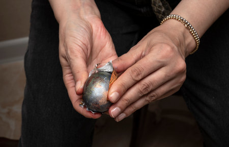 Close-up of female hands in the process of creating a festive Easter egg decoration for the Christian holiday at home. Studio photography.の写真素材