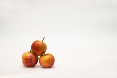 Red ripe apples are stacked in a small pyramid on a white background. Studio photography of fruits.の写真素材