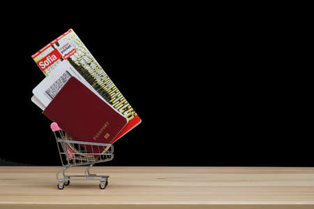 Travel kit - a small cart containing a passport, boarding pass and a map of the Bulgarian city of Sofia. Black background in a photo studio.の写真素材