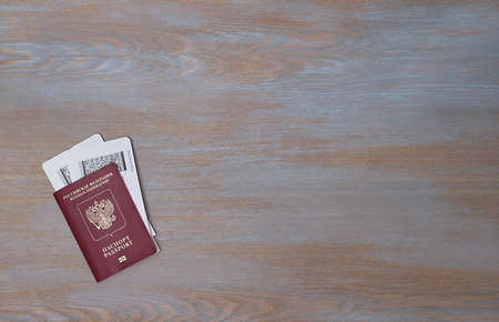 The Russian passport and boarding pass lie on a textured wooden surface. Travel documents - top view.のeditorial素材