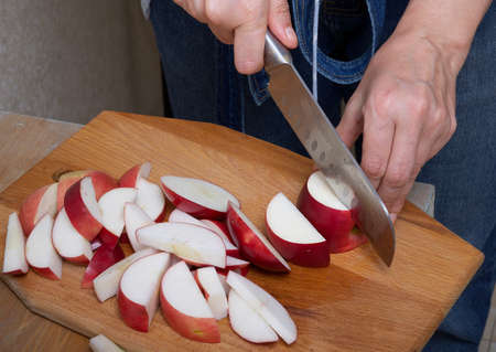 Female hands cut an apple into pieces in the process of making an apple pie in a home kitchen. Cooking a pie before the holiday.の写真素材