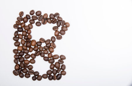 B is a capital letter of the English alphabet made up of natural roasted coffee beans that lie on a white background.の写真素材
