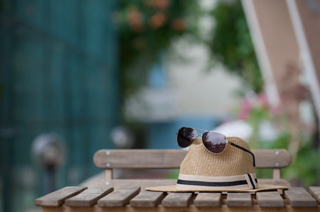 Summer hat and dark glasses lie on a small textured table on a summer evening as a symbol of carefree vacation.の写真素材