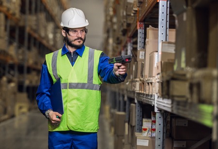 Man checking cargo on shelves with scannerの写真素材