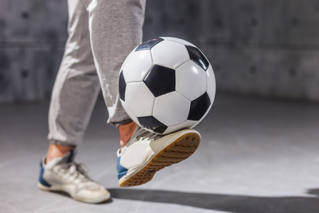 Man holds a soccer ball on his legの写真素材