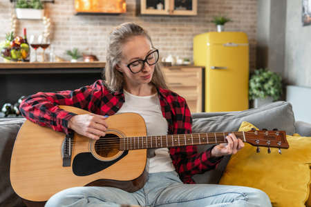 Woman is playing guitar at homeの写真素材