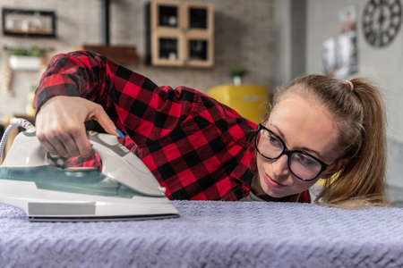 Woman looks at iron while ironingの写真素材