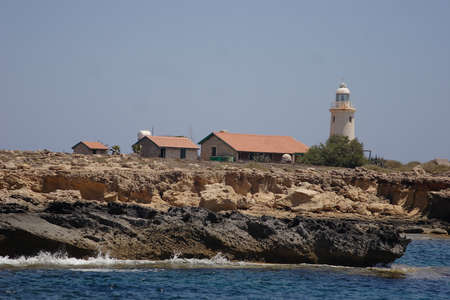 A lighthouse and small houses with tiled roofs on a stone cliff. High quality photoの写真素材