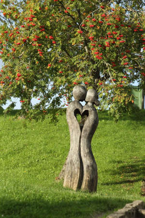Wooden sculpture of lovers on the background of a rowan tree, Kuldiga, Latvia. High quality photoの写真素材
