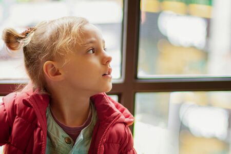 A little girl looks to the side by the windowの写真素材