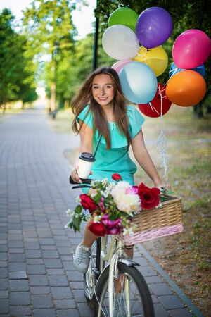 beautiful fashion girl with bicycle and balloons and coffeの写真素材