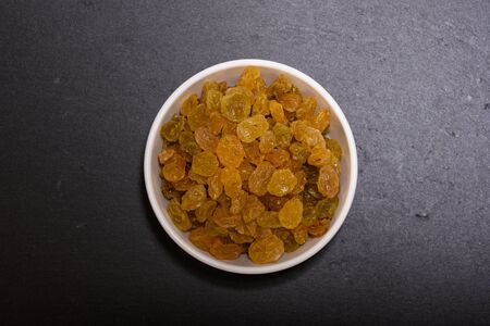 Raisins in white bowl on the black stone plateの写真素材