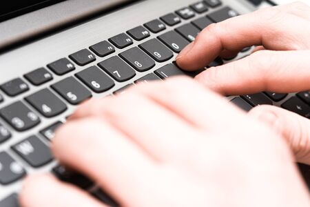 Hands typing on laptop keyboard