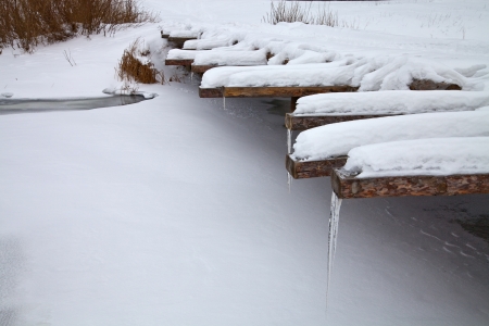 A wooden bridge across the frozen river in winterの写真素材