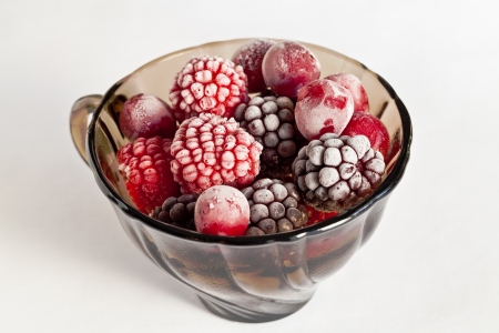 Frozen berries in a glass bowl on white backgroundの写真素材