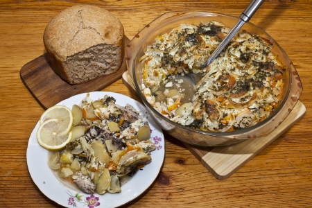 Baked fish with vegetables and bread on the tableの写真素材