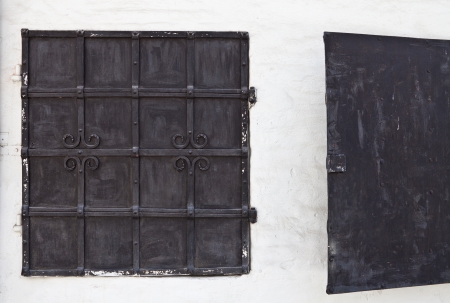Two old metal shutters on a white wallの写真素材