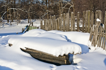 Wooden boat lies in the village yard in winterの写真素材
