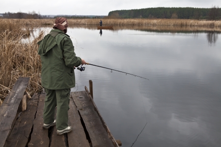Woman and men on a lake in autumn fishの写真素材