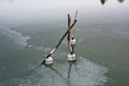 Wooden poles sticking out of the ice on the riverの写真素材