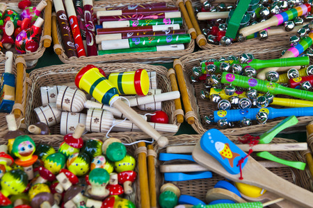 Many small wooden rattles of different colors in a wicker basket
