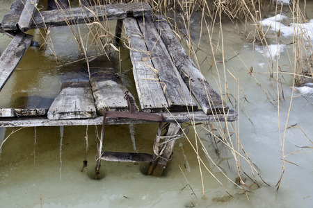 Old ruined wooden platform for fishing frozen into the iceの写真素材