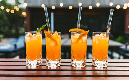 Cocktail glasses on outdoor bar tabr with orange drinks at shallow depth of fieldの素材