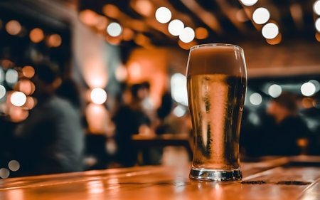 Beer in a glass on a bar under the bokeh lightの素材