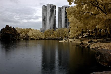 Infrared photo  lake, rock, apartment and tree in the parksの写真素材