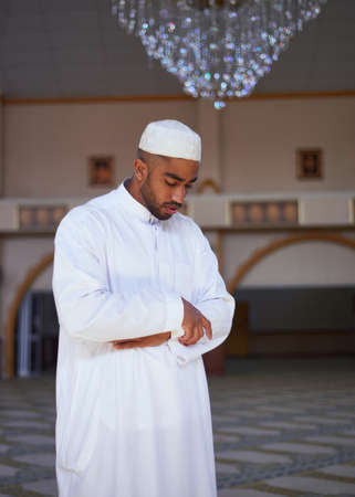 A portrait of young Muslim man standing during prayers at a mosqueの写真素材