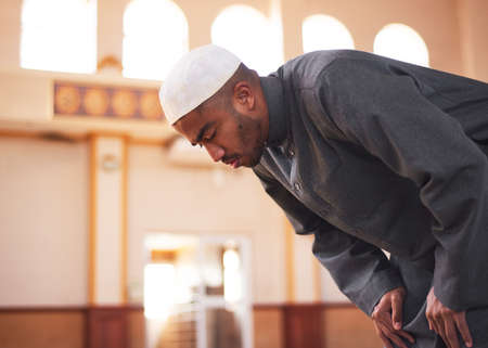 A side view of a Muslim man bowing during prayers at a mosqueの写真素材