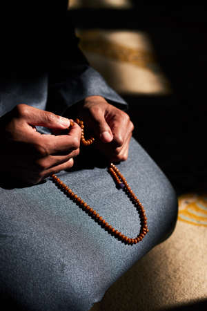 Close up of a Muslim mans hands holding prayer beads in a mosqueの写真素材