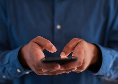 Close up shot of a man typing on a smart phoneの写真素材