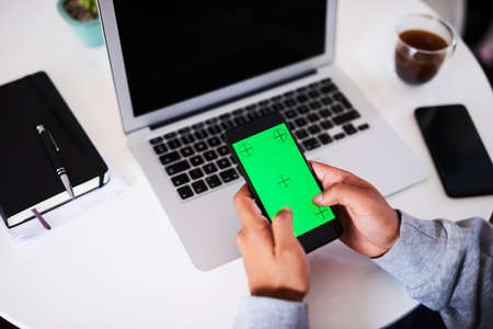 An over the shoulder shot of a young man typing on his mobile phone. Chroma keyの写真素材