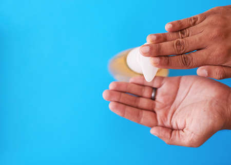 An overhead shot of a man dispensing soap against a blue backgroundの写真素材