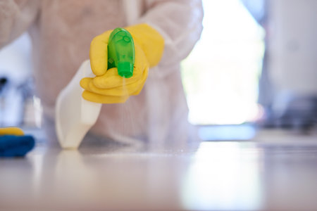 A cleaning professional sprays a kitchen counter with sanitiserの写真素材