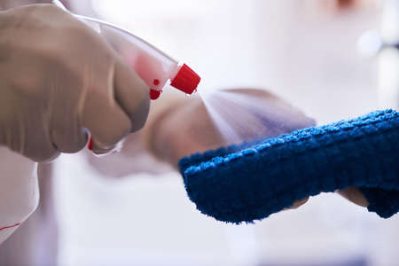 A cleaning professional sprays sanitiser onto a clothの写真素材