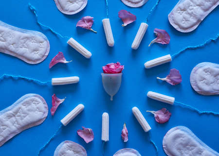 Period products surrounding a flower on a blue background.の写真素材