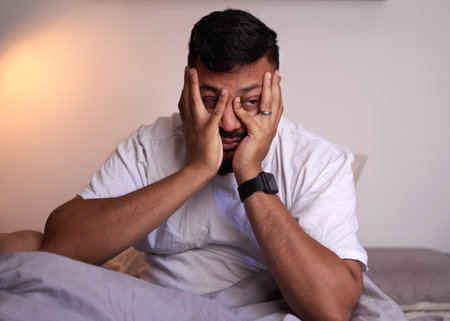 An adult man covers his face struggling to wake up in the early morningの写真素材