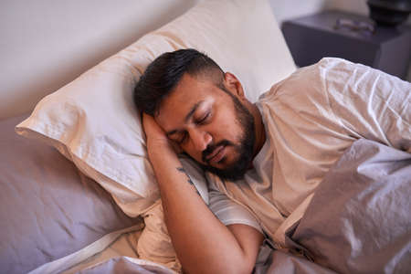 A man sleeps peacefully on his side in the early morningの写真素材