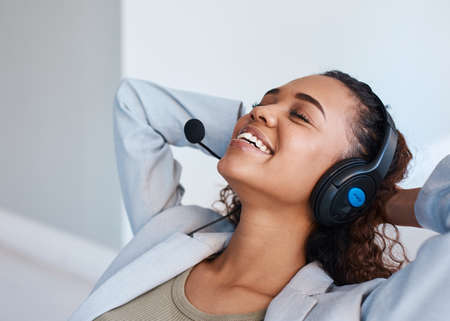 A young woman with a headset leans back and takes a break during the office day
