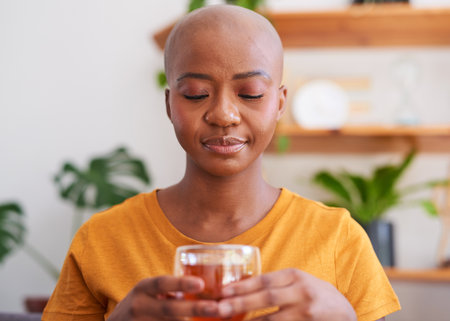 A young woman makes a cup of rooibos or red bush tea for health and wellnessの写真素材