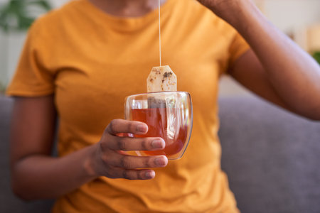 A young woman makes a cup of rooibos or red bush tea for health and wellnessの写真素材