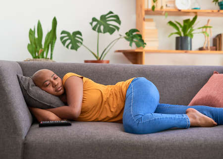 A young woman falls asleep watching TV on the sofa at homeの写真素材