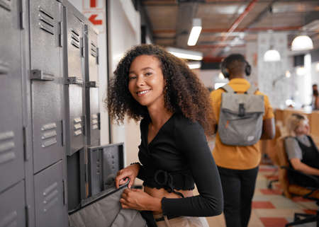 A young multi-ethnic woman gets ready for the college day at campus lockersの写真素材