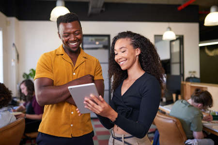 A young multi-ethnic woman shows her colleague a information on a digital tablet
