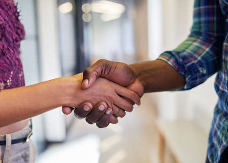 An extreme close up of a handshake where a man and woman shake hands