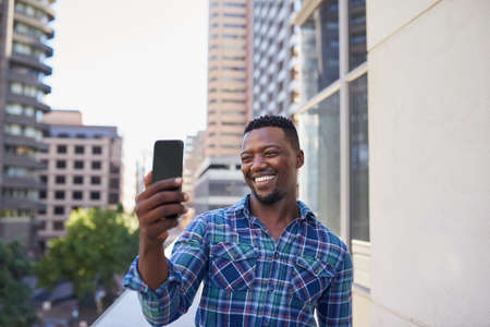 A Black businessman video calls on his office balcony in the city