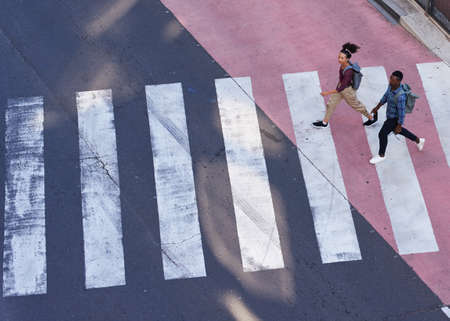 Two young pedestrians cross the road on a crosswalk in the cityの写真素材